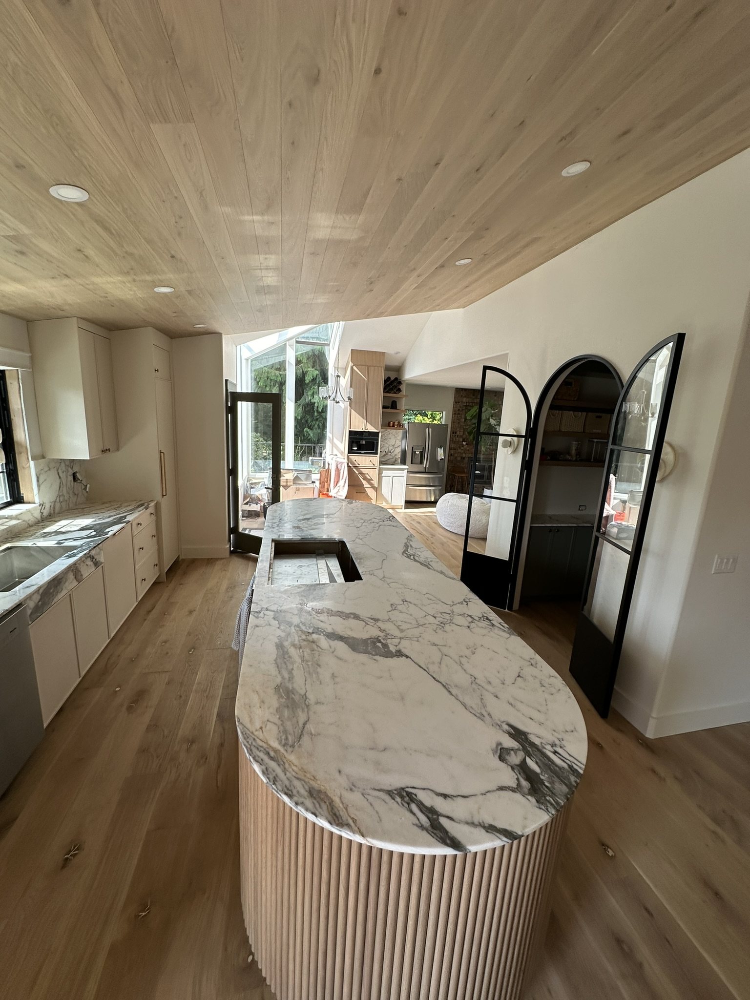 Custom curved stone island, cabinetry, and full-height stone surfaces by Viko Enterprise